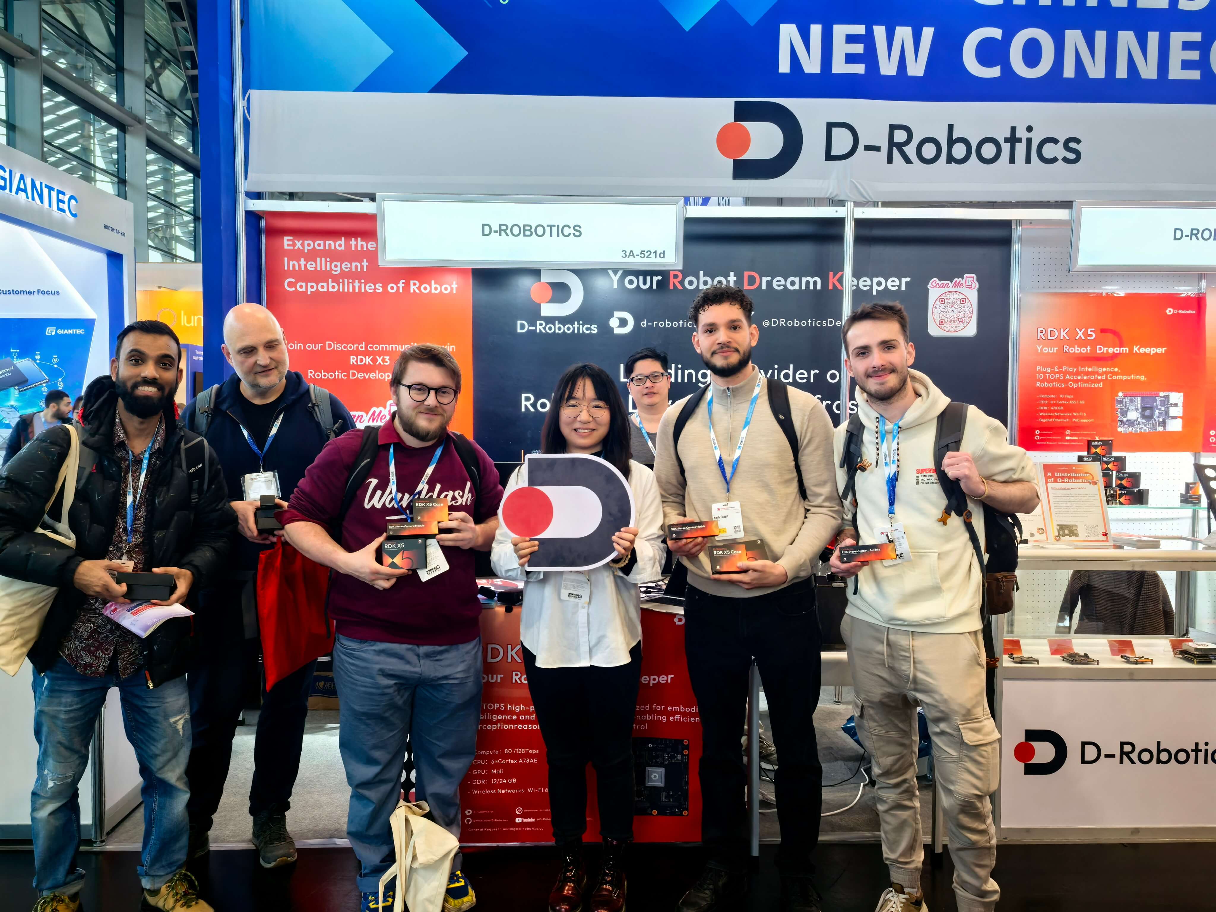This is a group photo in front of the D-Robotics booth at embeddedworld. A group of people are holding prizes, with brand logos and slogans in the background, brimming with the vitality of exhibition exchanges.
